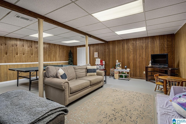 living room with a paneled ceiling and wooden walls