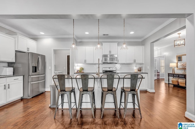 kitchen featuring backsplash, pendant lighting, a kitchen island with sink, white cabinets, and appliances with stainless steel finishes