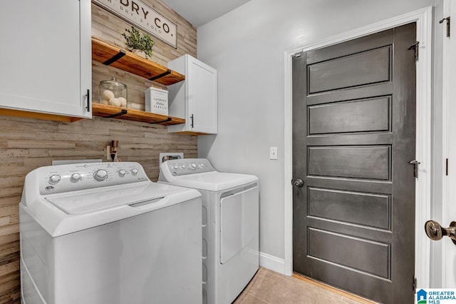 laundry area with wood walls, light tile patterned flooring, cabinets, and independent washer and dryer