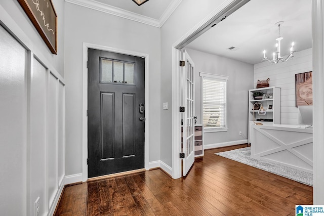 entryway with dark hardwood / wood-style flooring, ornamental molding, and a notable chandelier