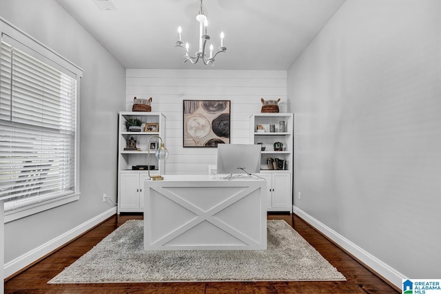 office space with wood walls, dark hardwood / wood-style floors, and an inviting chandelier