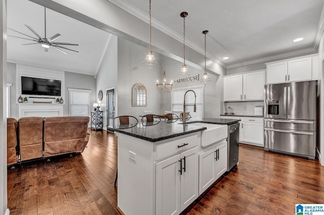 kitchen with dark stone countertops, a center island with sink, white cabinets, and appliances with stainless steel finishes