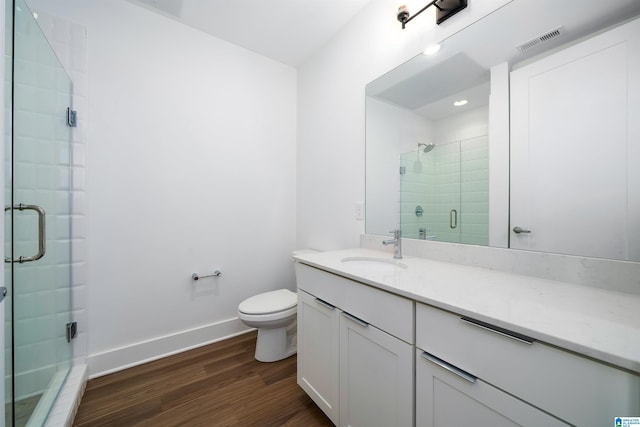 bathroom with a shower with door, vanity, wood-type flooring, and toilet