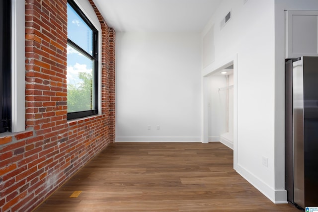 corridor with hardwood / wood-style flooring and brick wall