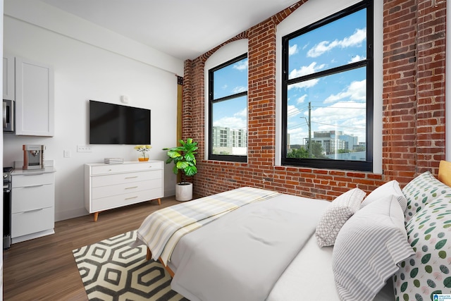 bedroom with dark hardwood / wood-style flooring and brick wall