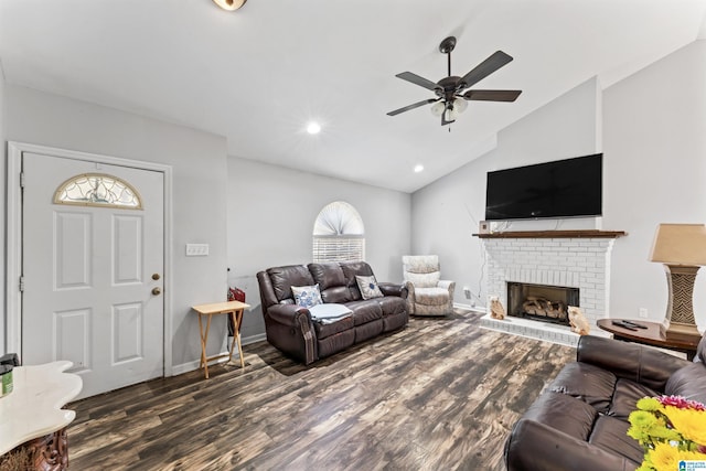 living room featuring ceiling fan, dark wood-type flooring, vaulted ceiling, and a brick fireplace