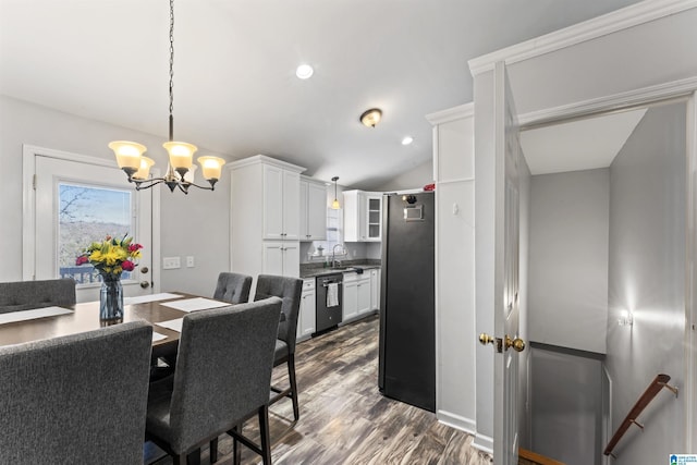 dining room with hardwood / wood-style flooring, a notable chandelier, sink, and vaulted ceiling