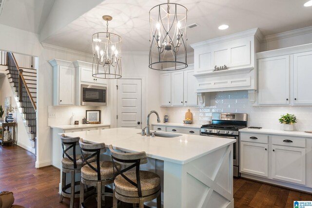 kitchen with pendant lighting, white cabinets, sink, gas range, and built in microwave