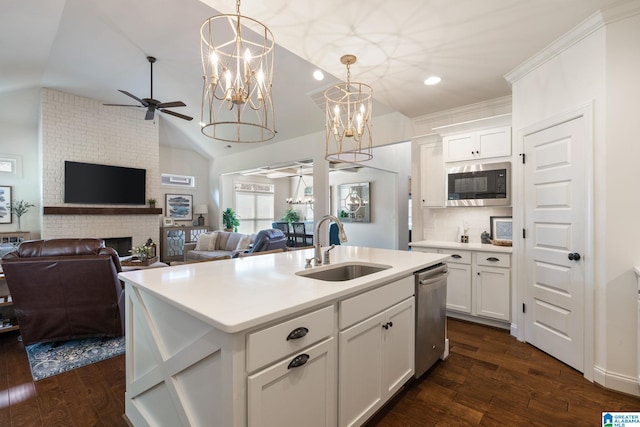 kitchen featuring built in microwave, white cabinetry, sink, an island with sink, and a fireplace