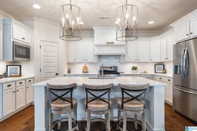 kitchen featuring a kitchen island with sink, white cabinets, and appliances with stainless steel finishes