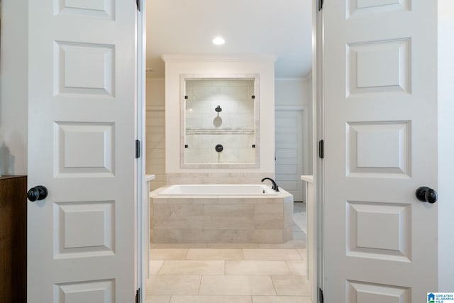 bathroom featuring crown molding, tile patterned flooring, and a relaxing tiled tub