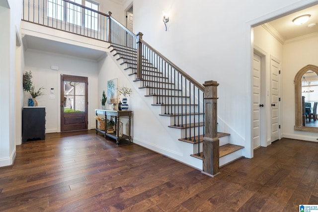 foyer featuring ornamental molding, a towering ceiling, a wealth of natural light, and dark wood-type flooring