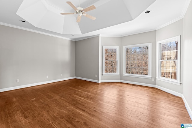 empty room featuring hardwood / wood-style flooring, ceiling fan, crown molding, and a tray ceiling