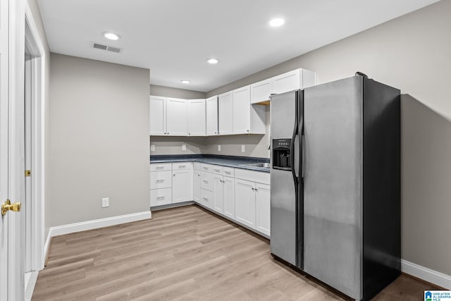 kitchen with white cabinetry, stainless steel refrigerator with ice dispenser, and light hardwood / wood-style flooring