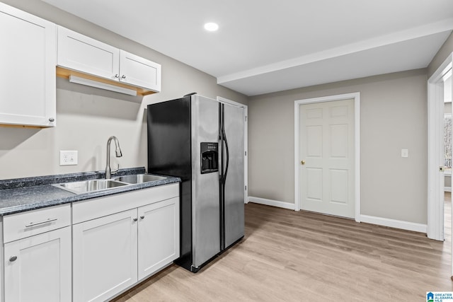 kitchen with white cabinets, stainless steel refrigerator with ice dispenser, light wood-type flooring, and sink