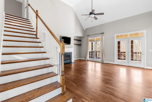 unfurnished living room featuring ceiling fan, plenty of natural light, high vaulted ceiling, and wood-type flooring