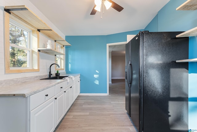 kitchen with decorative backsplash, light wood-type flooring, black fridge, sink, and white cabinets