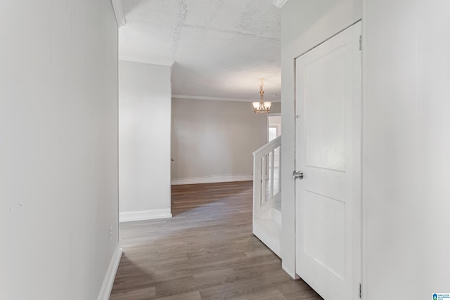 hallway with ornamental molding, light hardwood / wood-style floors, and a notable chandelier