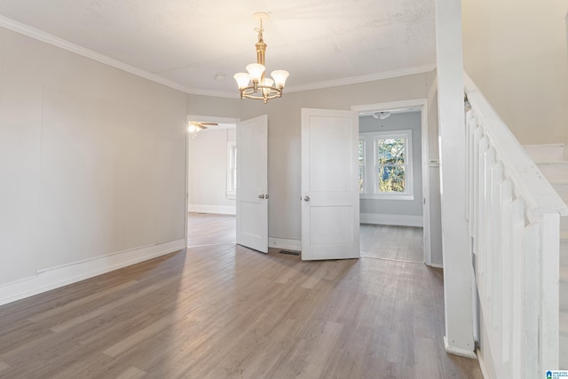 unfurnished room with ceiling fan with notable chandelier, light hardwood / wood-style floors, and ornamental molding