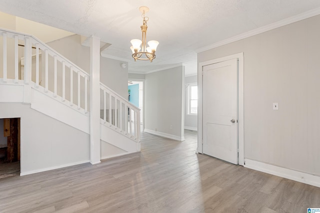 interior space with light hardwood / wood-style floors, ornamental molding, a textured ceiling, and a chandelier