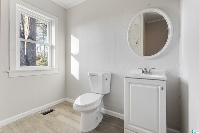 bathroom with wood-type flooring, vanity, toilet, and crown molding