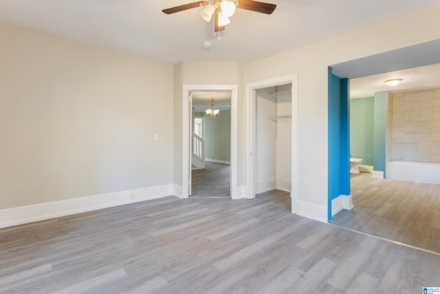 unfurnished bedroom with ceiling fan with notable chandelier, light hardwood / wood-style floors, a closet, and connected bathroom