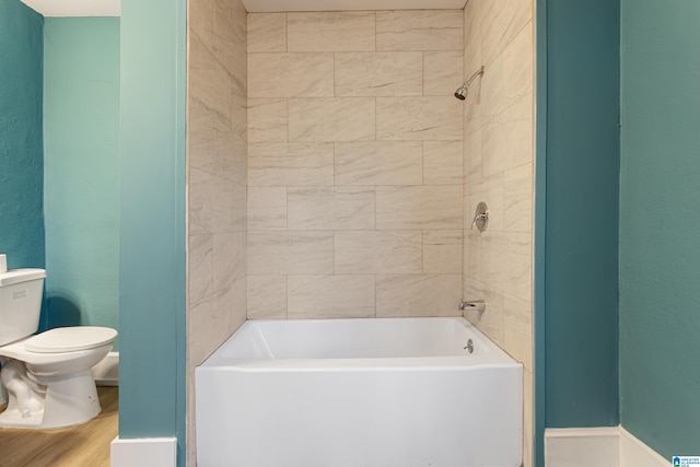 bathroom featuring toilet and tiled shower / bath