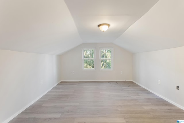 additional living space with light hardwood / wood-style floors and lofted ceiling