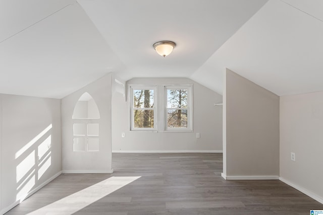 bonus room with vaulted ceiling and dark wood-type flooring