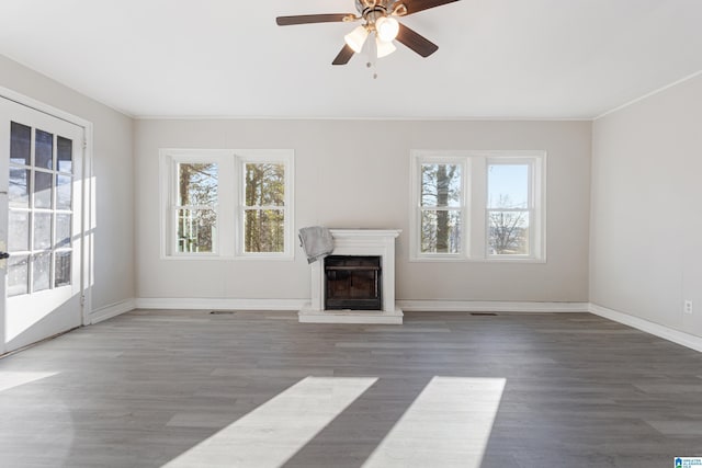 unfurnished living room featuring ceiling fan, crown molding, and dark wood-type flooring