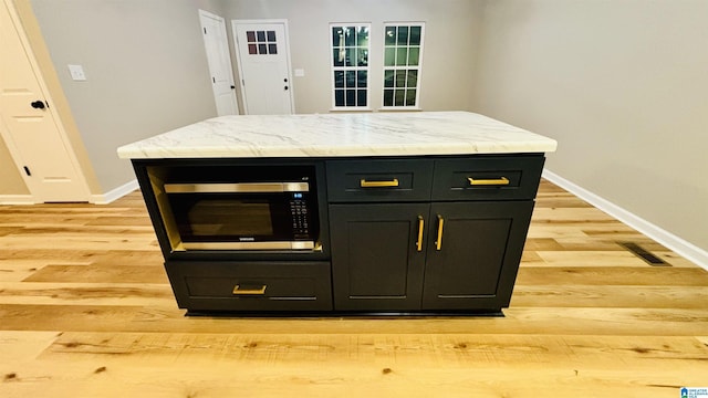 interior space featuring light stone countertops, light wood-type flooring, and a kitchen island