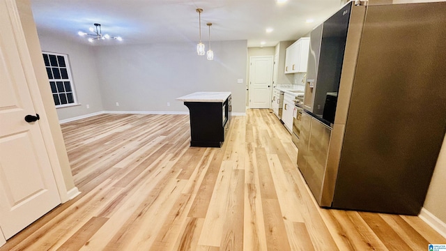 kitchen featuring pendant lighting, a center island, light wood-type flooring, white cabinetry, and stainless steel refrigerator