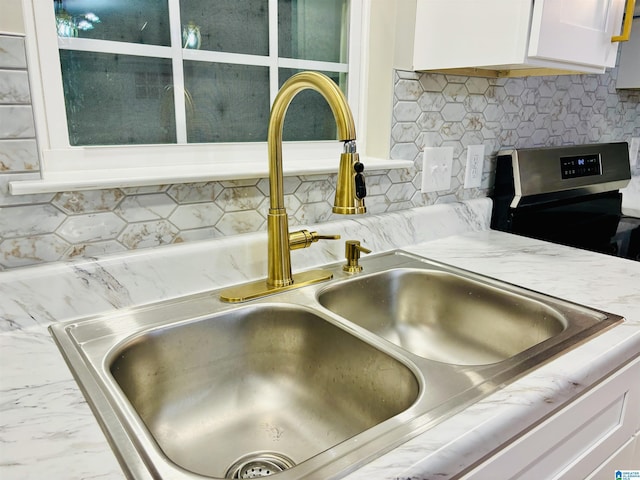 details featuring white cabinetry, sink, and tasteful backsplash