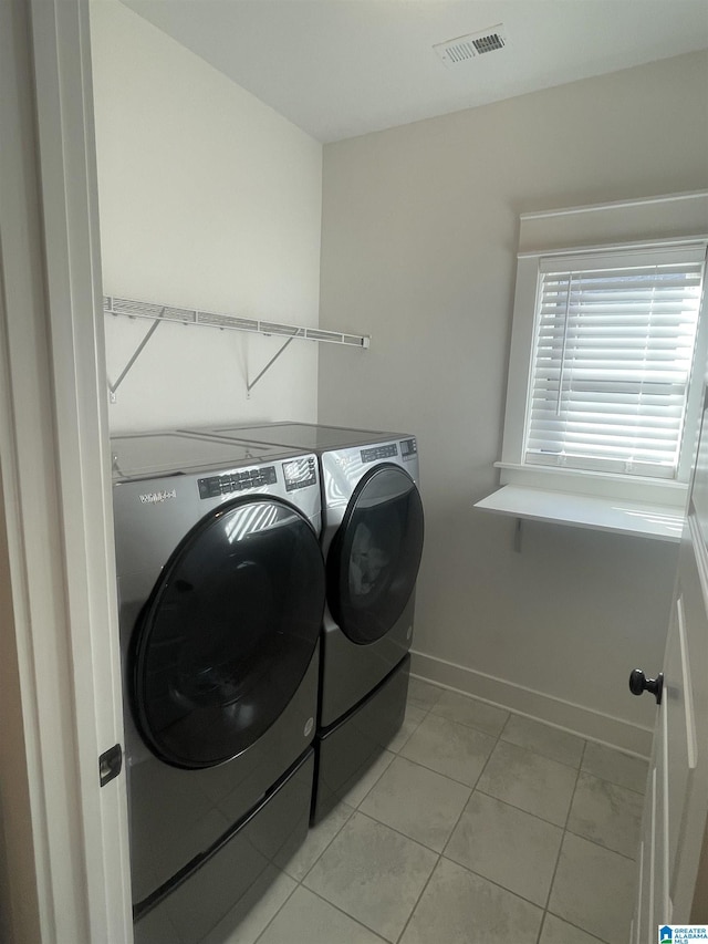 clothes washing area with light tile patterned floors and washing machine and clothes dryer