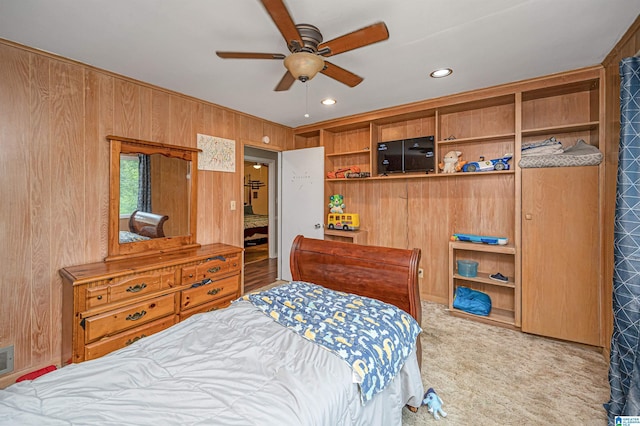 bedroom with light colored carpet, ceiling fan, and wooden walls