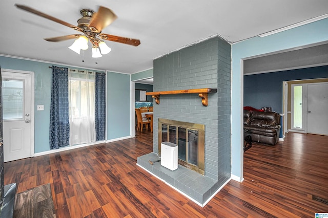 unfurnished living room with a fireplace, dark hardwood / wood-style floors, ceiling fan, and ornamental molding