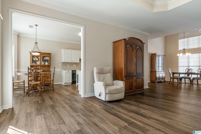 sitting room with dark wood-type flooring, a notable chandelier, and ornamental molding