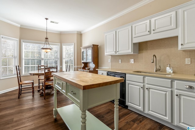 kitchen with dishwasher, pendant lighting, butcher block countertops, white cabinetry, and sink