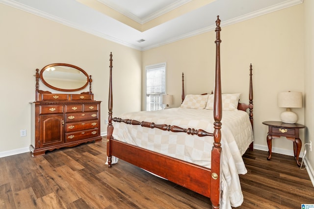 bedroom with dark wood-type flooring, ornamental molding, and a tray ceiling