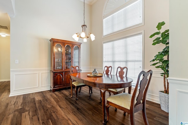 dining area with dark wood-type flooring, an inviting chandelier, and a wealth of natural light