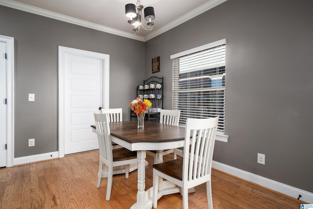 dining space with a chandelier, light wood-type flooring, and crown molding