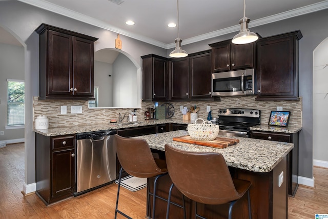 kitchen featuring decorative backsplash, light stone counters, stainless steel appliances, pendant lighting, and a center island