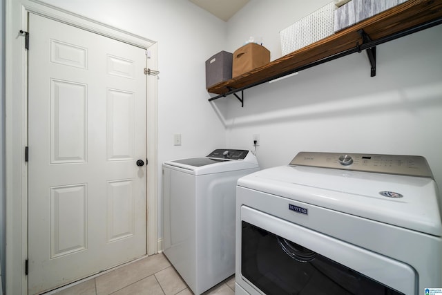 clothes washing area with light tile patterned floors and separate washer and dryer