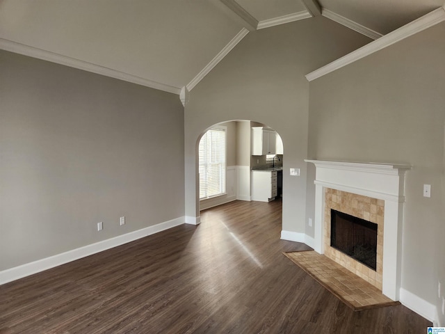 unfurnished living room featuring crown molding, a fireplace, sink, high vaulted ceiling, and dark wood-type flooring