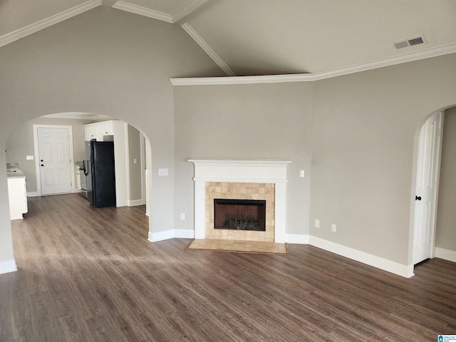 unfurnished living room featuring a tile fireplace, dark hardwood / wood-style floors, high vaulted ceiling, and ornamental molding