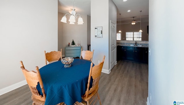 dining room with ceiling fan with notable chandelier, dark hardwood / wood-style flooring, and sink