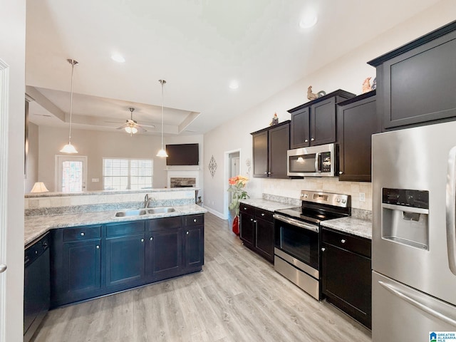 kitchen featuring pendant lighting, sink, ceiling fan, appliances with stainless steel finishes, and a tray ceiling