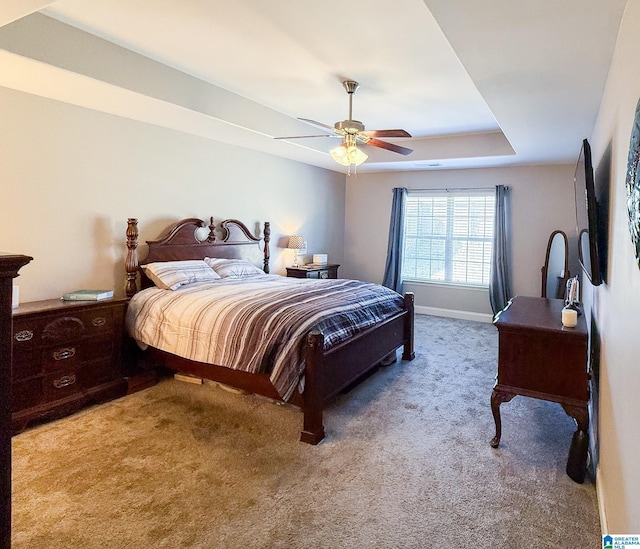 bedroom with ceiling fan, a raised ceiling, and light colored carpet