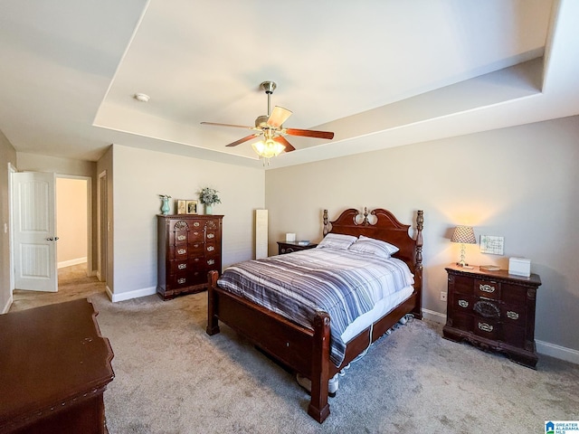 bedroom featuring ceiling fan, a raised ceiling, and light carpet