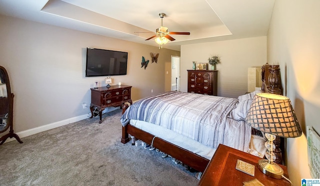 bedroom with carpet flooring, a tray ceiling, and ceiling fan